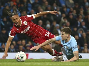 Manchester City's John Stones, right, challenges for the ball with with Bristol City's Bobby Reid during the English League Cup semifinal first leg soccer match between Manchester City and Bristol City at the Etihad stadium in Manchester, England, Tuesday, Jan. 9, 2018.