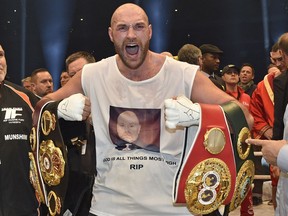 FILE - In this Nov. 29, 2015 file photo, Britain's then new world champion Tyson Fury, celebrates with the WBA, IBF, WBO and IBO belts after winning the world heavyweight title fight against Ukraine's Wladimir Klitschko in Duesseldorf, western Germany. Former world heavyweight champion Tyson Fury is set to regain his boxing license. The British Boxing Board of Control interviewed Fury on Friday, Jan. 19, 2018 and said the suspension of the fighter's license "will be lifted subject to receipt and clearance of all medical requirements."