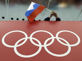 FILE - In this Feb. 18, 2014 file photo, a Russian skating fan holds the country's national flag over the Olympic rings at Adler Arena Skating Center during the 2014 Winter Olympics in Sochi, Russia. The Court of Arbitration for Sport has received 20 more appeals from Russian athletes against Olympic doping bans, taking the total to 42. The athletes' appeals will be fast-tracked. CAS said those cases will be heard together in the week beginning Jan. 22, and it expects verdicts will be issued by Jan. 31.