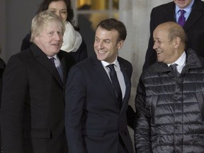 British Foreign Secretary Boris Johnson, left, with French President Emmanuel Macron, and Laurent Fabius, prepare for a group photo during UK-France summit talks at the Royal Military Academy Sandhurst, in Camberley, England, Thursday Jan. 18, 2018.  The leaders announced that police and security services from France and England will meet to help combat extremism and terrorist threats.