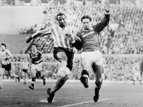 FILE - In this file photo dated Jan.31, 1987, Coventry City's Cyrille Regis, left, and Manchester United's John Sivebaek, in Manchester, England.  Monday January 15, 2018. Cyrille Regis, a pioneer for black footballers in England who endured racist abuse while forging a career with West Bromwich Albion and playing for England, has died aged 59, according to an announcement issued from Professional Footballers' Association.