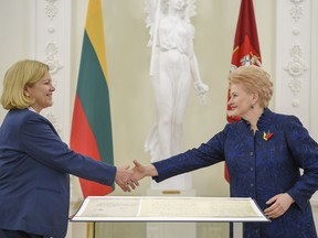 Head of the Political Archive of the Federal Foreign Office of Germany, Professor Elke von Boeselager, left, shakes hands with Lithuania's President Dalia Grybauskaite after handing over Independence act Wednesday Jan. 17, 2018 at president's office in Vilnius. The copy of the Lithuania 1918 Independence Act found in the archives of Germany's foreign ministry, has been returned to the Baltic country but only on loan.  (Lithuanian President Press Service via AP)