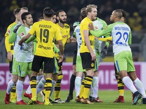 Wolfsburg's Marcel Tisserand, right, and Dortmund's Andre Schurrle, 2nd right, face off at the German Bundesliga soccer match between Borussia Dortmund and VfL Wolfsburg, in Dortmund, Germany, Sunday, Jan. 14, 2018.