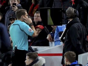 Match referee Craig Pawson uses the Video Assistant Referee to give a penalty to Liverpool during the English FA Cup, fourth round soccer match between Liverpool and West Bromwich Albion, at the Anfield stadium, Liverpool, England, Saturday Jan. 27, 2018.