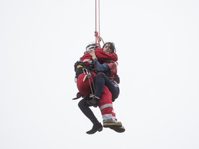 Marisa Lazo is rescued by firefighter Rob Wonfor after she climbed onto a crane in downtown Toronto.