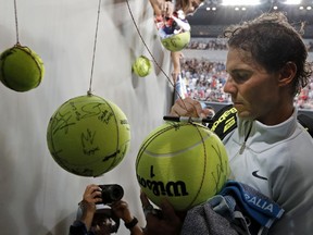 Spain's Rafael Nadal signs autographs after defeating Damir Dzumhur of Bosnia and Herzegovina in their third round match at the Australian Open tennis championships in Melbourne, Australia, Friday, Jan. 19, 2018.