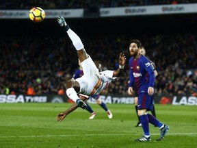 Alaves' Mubarak Wakaso, left, attempts an overhead kick against FC Barcelona's Lionel Messi during the Spanish La Liga soccer match between FC Barcelona and Alaves at the Camp Nou stadium in Barcelona, Spain, Sunday, Jan. 28, 2018.