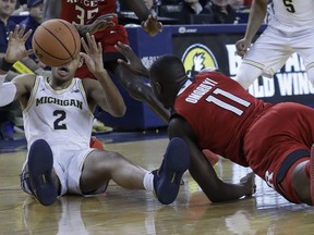 Rutgers forward Eugene Omoruyi (11) and Michigan guard Jordan Poole (2) chase the loose ball during the first half of an NCAA college basketball game, Sunday, Jan. 21, 2018, in Ann Arbor, Mich.