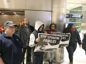 In this Monday, Jan. 15, 2018 photo, supporters of Jorge Garcia hold up signs that read "Stop Separating Families" at Detroit Metro Airport. Garcia was being deported to Mexico after living in the U.S. for nearly 30 years.