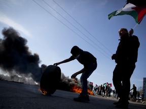 A Palestinian protester burn tires following protests against US. President Donald Trump's decision to recognize Jerusalem as the capital of Israel, in the West Bank city of Ramallah, Tuesday, Jan. 9, 2018.