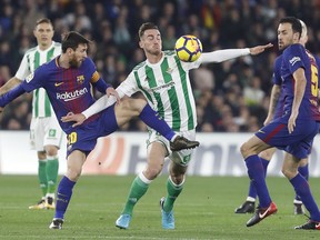 Barcelona's Messi, left, and Betis' Fabian, centre, fight for the ball during La Liga soccer match between Barcelona and Betis at the Villamarin stadium, in Seville, Spain on Sunday, Jan. 21, 2018.