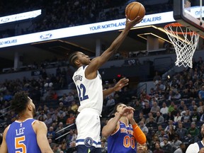 Minnesota Timberwolves' Andrew Wiggins, center, lays up a shot as New York Knicks' Courtney Lee, left, and Enes Kanter, of Turkey, watch in the first half of an NBA basketball game Friday, Jan. 12, 2018, in Minneapolis.