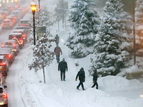 Backup traffic waits at a light as pedestrians arrive at Xcel Arena for a Minnesota Wild and Ottawa Senators NHL hockey game Monday, Jan. 22, 2018, in St. Paul, Minn. as heavy snow and strong winds are pushing through the Midwest.