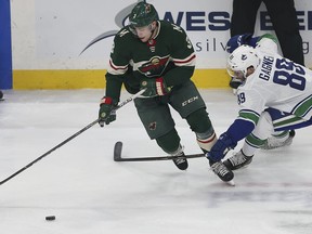 Minnesota Wild's Charlie Coyle (3) and Vancouver Canucks Sam Gagner (89) go after the puck in the first period of an NHL hockey game Sunday, Jan. 14, 2018, in St. Paul, Minn.