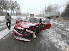 Brandon Reddout looks at the damage done to his car after he was struck by a tractor trailer which ran off the road shortly after the collision on West Main Street in Tupelo Mississippi Tuesday morning, Jan. 16, 2018.