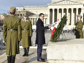 Staying on an official visit in Hungary new Polish Prime Minister Mateusz Morawiecki arranges ribbons as he lays a wreath at the Memorial Stone of Heroes on the Heroes' Square in Budapest Wednesday, Jan. 3, 2018.