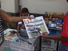 FILE - In this Dec. 20, 2017 file photo, a man buys a newspaper carrying the Spanish headline "They killed Gumaro!" on the sidewalk in Acayucan, Veracruz state, Mexico. For some, Gumaro Perez was an experienced reporter who earned the nickname "the red man" for his coverage of bloody crimes in Acayucan, Veracruz, but in the eyes of prosecutors he was an alleged drug cartel operative who met a grisly end when he was shot dead Dec. 19.