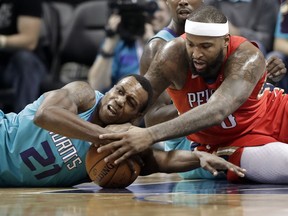 Charlotte Hornets' Treveon Graham (21) and New Orleans Pelicans' DeMarcus Cousins (0) battle for a loose ball during the first half of an NBA basketball game in Charlotte, N.C., Wednesday, Jan. 24, 2018.