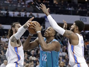 Charlotte Hornets' Dwight Howard, center, drives between Oklahoma City Thunder's Paul George, right, and Steven Adams, left, during the first half of an NBA basketball game in Charlotte, N.C., Saturday, Jan. 13, 2018.