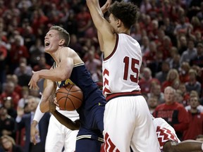 Michigan's Moritz Wagner (13) is fouled by Nebraska's Glynn Watson Jr., right rear, as Isaiah Roby (15) guards during the first half of an NCAA college basketball game in Lincoln, Neb., Thursday, Jan. 18, 2018.