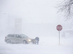 Daniel Marks digs his car out after getting stuck in a snowstorm Monday, Jan 22, 2018, in Norfolk, Neb.