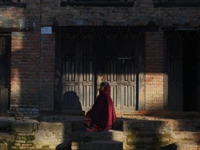 A Nepalese elderly woman sits in front of her house as she tries to get some sunshine on a cold day in Bungamati, Lalitpur, Nepal.