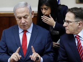 Israeli Prime Minister Benjamin Netanyahu, left, listens to an advisor as he sits next to Cabinet Secretary Tzachi Braverman at the start of a cabinet meeting, in Jerusalem, Sunday, Dec. 31, 2017.