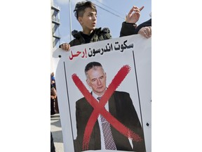 A protester holds a banner with a defaced picture of Scott Anderson, director of operations for the United Nations Relief and Works Agency, UNRWA, in the West Bank, during a joint protest for UNRWA employees and Palestinian refugees against U.S. funding cuts, in front of the Pa alestinian prime minister's office, in the West Bank city of Ramallah, Tuesday, Jan. 30, 2018. Earlier this month, the Trump administration slashed $60 million of a planned $125 million funding installment for 2018. Arabic reads, "Scott Anderson, leave."