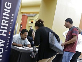 FILE - In this Tuesday, Oct. 3, 2017, file photo, job seekers stand at a booth at a job fair at the Dolphin Mall in Sweetwater, Fla.  U.S. businesses kept hiring at a healthy pace in January 2018, a sign the economy is off to a solid start for the year, a private survey found. Payroll processor ADP says that companies added 234,000 jobs, led by big gains in services firms, such as hotels, restaurants, retail, education and health.