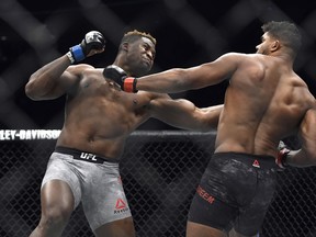 FILE- In this Dec. 2, 2017, file photo, Francis Ngannou, left, hits Alistair Overeem in the first round during a UFC 218 heavyweight mixed martial arts bout, in Detroit. Ngannou defeated Overeem by first-round knockout. Ngannou has knockout power that snaps heads back like Pez dispensers and earned him comparisons to Mike Tyson in his ferocious heyday. Ngannou will compete in the heavyweight champion bout against Stipe Miocic in the main event of UFC 220.