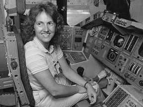 FILE - In this Sept. 13, 1985 file photo, Christa McAuliffe tries out the commander's seat on the flight deck of a shuttle simulator at the Johnson Space Center in Houston, Texas. Thirty-two years after the Challenger disaster, a pair of teachers turned astronauts on the International Space Station will pay tribute to McAuliffe by carrying out her science classes.