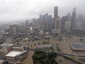 FILE- In this Aug. 29, 2017, file photo, highways around downtown Houston are empty as floodwaters from Tropical Storm Harvey overflow from the bayous around the city in Houston. With three strong hurricanes, wildfires, hail, flooding, tornadoes and drought, supersized weather disasters tallied a record high bill for America last year: $306 billion.