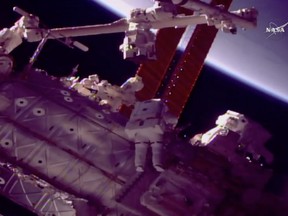 NASA astronauts Mark Vande Hei, left, and Scott Tingle work outside the International Space Station on Tuesday, Jan. 23, 2018, to give the robot arm a new hand. (NASA TV via AP)