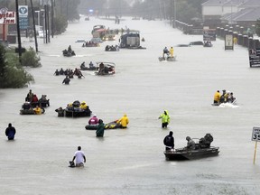 FILE - In this Aug. 28, 2017, file photo, rescue boats float on a flooded street as people are evacuated from rising floodwaters brought on by Tropical Storm Harvey in Houston. The National Hurricane Center's official report on Harvey compiles staggering numbers, starting with 68 dead and $125 billion in damage. But the really big numbers in the Thursday, Jan. 25, 2018, tally have to do with the rainfall that swamped Houston. Two places had more than five feet of rain. Eighteen different parts of Texas logged more than four feet of rain.