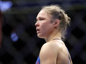 FILE - In this Dec. 30, 2016, file photo, Ronda Rousey stands in the cage after Amanda Nunes forced a stoppage in the first round of their women's bantamweight championship mixed martial arts bout at UFC 207 in Las Vegas. The former UFC champion Rousey could soon make the move to WWE. She's met with WWE executives and has seemed excited about the possibility of becoming a wrestler. Rousey may not debut at one of WWE's signature events this weekend in Philadelphia because she's filming a movie in Colombia.