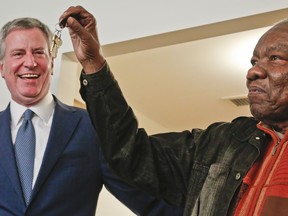 Jasper Hurst, 79, right, show keys he received from Mayor Bill de Blasio, left, after he signed a lease inside his new affordable apartment, Tuesday Jan. 16, 2018, at the Cypress Hills Senior Residences in Brooklyn, New York.