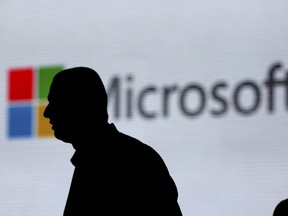 FILE - In this Tuesday, Nov. 7, 2017, file photo, an unidentified man is silhouetted as he walks in front of Microsoft logo at an event in New Delhi, India. Microsoft Corp. reports earnings Wednesday, Jan. 31, 2018.