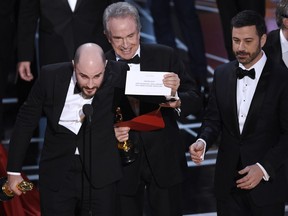 FILE - In this Feb. 26, 2017, file photo, Jordan Horowitz, producer of "La La Land," left, shows the envelope revealing "Moonlight" as the true winner of best picture at the Oscars in Los Angeles as presenter Warren Beatty and host Jimmy Kimmel, right, look on. The film academy and its accounting firm, PwC, are announcing a spate of new rules Monday, Jan. 22, 2018, meant to avoid an envelope gaffe like at last year's show, when "La La Land" was mistakenly announced as the winner instead of "Moonlight." PwC U.S. Chairman Tim Ryan said the new protocols include additional personnel and oversight, as well as practicing what to do if a presenter reads the wrong name.