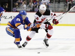 New York Islanders' Sebastian Aho (28) and New Jersey Devils' Miles Wood (44) fights for control of the puck during the first period of an NHL hockey game Tuesday, Jan. 16, 2018, in New York.