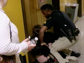 In this Monday, Jan. 8, 2018, image made from a video provided by KATC-TV middle-school English teacher Deyshia Hargrave is handcuffed by a city marshal after complying with a marshal's orders to leave a Vermilion Parish School Board meeting in Abbeville, La., west of New Orleans. Hargrave was removed from the school board meeting, forcibly handcuffed and jailed after questioning pay policies during a public comment period. (KATC-TV via AP)