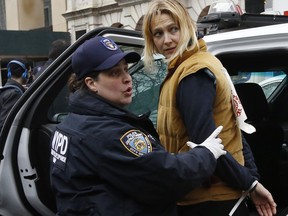 A New York City Police officer shouts to a colleague as she leads protester Maria Hunken to a squad car after Hunken and others were arrested demonstrating against the detention of prominent immigration rights activist Ravi Ragbir, Thursday, Jan. 11, 2018, in New York. Ragbir's attorney said her client was handcuffed and detained by federal authorities during a scheduled immigration check-in in lower Manhattan. Ragbir has been fighting deportation for years.