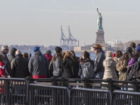 Visitors to the Statue of Liberty stand in line to board a ferry that will cruise the bay around the statue and Ellis Island, Saturday, Jan. 20, 2018, in New York. The National Park Service announced that the Statue of Liberty and Ellis Island would be closed Saturday "due to a lapse in appropriations." Late Friday, the Senate failed to approve legislation to keep the government from shutting down after the midnight deadline.