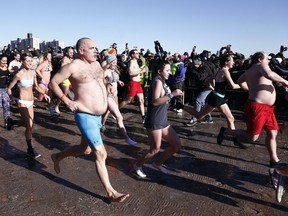 People taking part in Coney Island's annual New Year's Day Polar Plunge race across the beach towards the water in New York, on Monday, Jan. 1, 2018. Temperatures hovered at about 17 degrees (-8 Celsius) for the annual tradition that began in 1903.