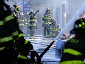 FILE- In this Jan. 2, 2018, file photo, firefighters are covered with ice from water sprayed from their hoses as they work to contain a fire in the Bronx section of New York. Firefighters battling blazes in the extreme cold are faced with treacherous conditions that can slow them down when every second counts.