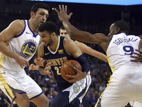Denver Nuggets' Jamal Murray, center, drives the ball between Golden State Warriors' Zaza Pachulia, left, and Andre Iguodala (9) during the first half of an NBA basketball game Monday, Jan. 8, 2018, in Oakland, Calif.