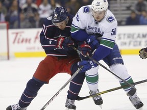 Columbus Blue Jackets' Markus Hannikainen, left, of Finland, and Vancouver Canucks' Brendan Gaunce fight for the puck during the first period of an NHL hockey game Friday, Jan. 12, 2018, in Columbus, Ohio.