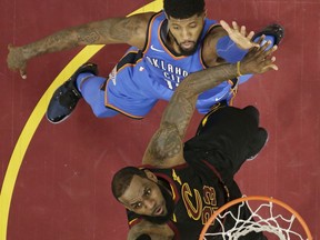 Cleveland Cavaliers' LeBron James, left, drives to the basket against Oklahoma City Thunder's Paul George in the first half of an NBA basketball game, Saturday, Jan. 20, 2018, in Cleveland.