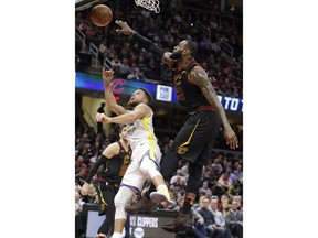 Cleveland Cavaliers' LeBron James blocks a shot by Golden State Warriors' Stephen Curry, left, in the second half of an NBA basketball game, Monday, Jan. 15, 2018, in Cleveland.
