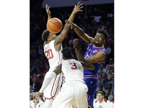 Kansas's Udoka Azubuike (35) throws the ball away from Oklahoma's Kameron McGusty (20) and Khadeem Lattin (3) during the first half of an NCAA college basketball game in Norman, Okla., Tuesday, Jan. 23, 2018.