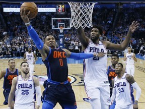 Oklahoma City Thunder guard Russell Westbrook (0) shoots in front of Philadelphia 76ers center Joel Embiid (21) in the first half of an NBA basketball game in Oklahoma City, Sunday, Jan. 28, 2018.